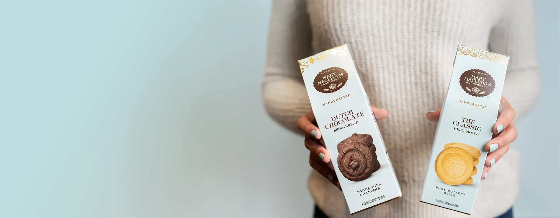 Image of a person holding two Mary Macleod's Shortbread packages against a light background.